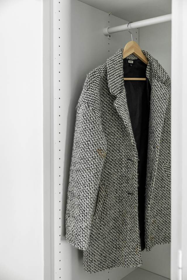 Een wollen damesjas aan een hanger